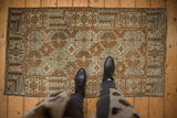 Vintage distressed Belouch rug showing faded geometric patterns in bronze, ivory, and soft silver.