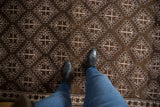 Vintage distressed Oushak rug's chocolate brown and silver geometric serrated medallion pattern underfoot.