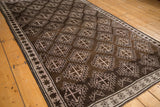 Distressed Oushak rug featuring chocolate brown serrated medallions, pale mauve starburst border, and even wear.