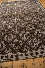 Distressed Oushak rug border with chocolate brown starburst design on pale mauve.