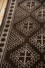 Vintage distressed Oushak rug detail: chocolate brown serrated motifs and starburst border.