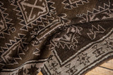 Vintage distressed Oushak rug close-up: chocolate brown, silver serrated patterns and starburst border.