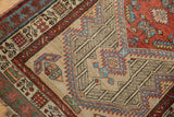 Vintage Serab rug with geometric serrated mahi-mahi patterns in sand, red, and sky blue.