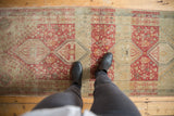 A look down at the distressed texture and geometric medallion of a vintage Shiraz runner.