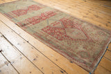 Long angled view of a vintage Shiraz runner's distressed texture and repeating raspberry medallions.