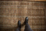 Distressed Belouch rug detail: geometric guls in coffee bronze, slate blue, and visible wear.