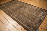 Geometric patterns in slate blue and pale coffee bronze on a distressed Belouch rug.