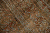 Worn pile texture of vintage Belouch rug, revealing geometric guls in bronze and slate blue.