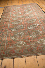 Distressed vintage Belouch rug with terra cotta Bokhara guls and a geometric border.
