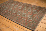 Vintage distressed Belouch rug with terra cotta guls, unique halved medallions, and worn texture.