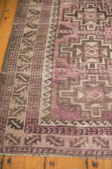 Distressed Belouch rug detail: purple, charcoal geometric meandering leaf and wave borders.