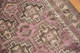 Distressed Belouch rug detail showing geometric wave borders in purple, charcoal, and ivory.