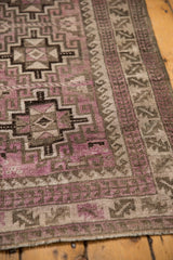 Distressed purple and charcoal repeating geometric medallions with faint foundation on the vintage Belouch runner.