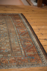 Distressed Belouch rug corner, madder root red meandering vine and sky blue wave borders.