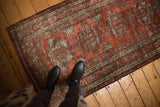 Distressed vintage Belouch rug showing worn texture, brick red and slate geometric palmette patterns.