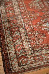 Distressed geometric border pattern in brick red and slate silver, with visible even wear.