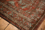 Distressed texture and brick red, slate silver patterns on vintage Belouch rug corner.