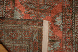 Distressed brick red and slate gray pile contrasts with the hand-knotted foundation.