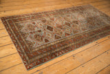 Distressed Belouch rug runner with repeating lattice, floral panels, and borders in slate blue and madder red.