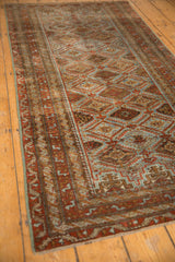 Distressed vintage Belouch runner: geometric lattice with floral panels in slate blue and rust tones.