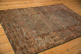 Belouch rug corner detail: distressed geometric rams horn motifs in terracotta, rust, and slate blue.