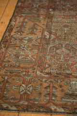 Distressed vintage Belouch rug's textured pile and geometric motifs in terracotta, slate blue.