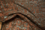 Textured distressed Belouch rug pile, showing rust and slate blue geometric designs.