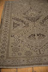 Distressed vintage Belouch rug detail showing sand, charcoal rams horn, starburst motifs, and border.