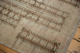 Distressed texture of vintage Belouch rug with coffee brown tree of life motif on worn neutral tones.
