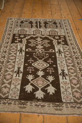 Vintage Persian Belouch rug featuring tribal figures and geometric motifs in chocolate brown and ivory.