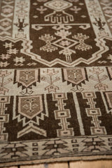 Distressed vintage Belouch rug detail with germinating plant motifs on chocolate brown and ivory field.