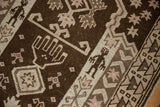 Chocolate brown and antique ivory distressed pile on a vintage Belouch rug with tribal figures.