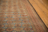 Distressed vintage Belouch rug with dusty blue and madder red floral design, showing low pile.