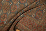 Folded hand-knotted vintage Belouch rug showing distressed texture and geometric patterns.