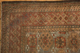 Distressed Belouch rug corner, showcasing even wear, madder root, slate blue geometric motifs.