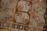 Distressed Belouch rug: visible wear, double gul motif, abrashed chestnut, coffee, and silver tones.