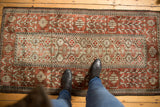A personal perspective of a distressed Persian Belouch rug, showing texture and scale.
