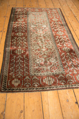 Angled view of a vintage Belouch rug, showcasing its distinctive wide border and panelled central field.