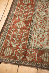 A vintage Belouch rug's corner featuring a wide border and geometric reciprocating wave motifs.