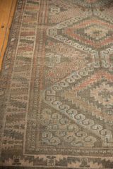 Distressed Belouch rug pile displaying muted red, powder blue, and beige scalloped hook motifs.