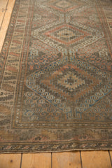 Distressed low pile and scrolling hook and latch motifs on vintage Belouch rug.