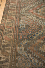 Distressed brown, red, and blue geometric and scrolling patterns on a vintage Belouch rug.