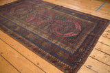 Distressed antique Belouch corner rug, showing sapphire blue border, tribal motifs, and foundation wear.