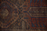 Distressed antique Belouch rug pile, showing geometric patterns in madder red and sapphire blue.