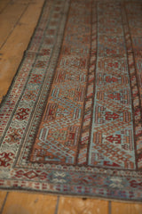 Distressed Persian Belouch rug detail: geometric channels in chestnut, slate, and brick red.