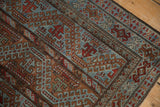 Distressed Belouch rug corner with worn pile, slate blue, and elaborate geometric vine motifs.