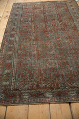 Distressed vintage Belouch rug, showing muted brick red and slate blue geometric pattern with wear.