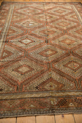 Distressed Belouch carpet detail with geometric medallions, hook motifs, in terracotta and beige.