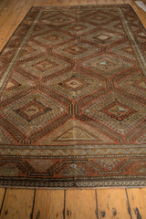 Belouch carpet border, hook and latch medallions, distressed terracotta, brown, and slate blue.