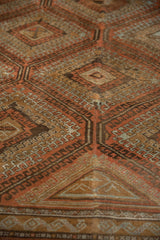 Distressed vintage Belouch carpet pile, showing terracotta geometric medallions and hook motifs.